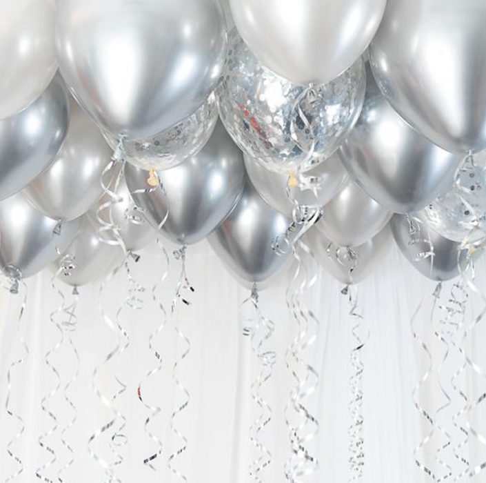 Många silverfärgade ballonger som sitter fast i ett tak med vackra silvriga snören hängande under