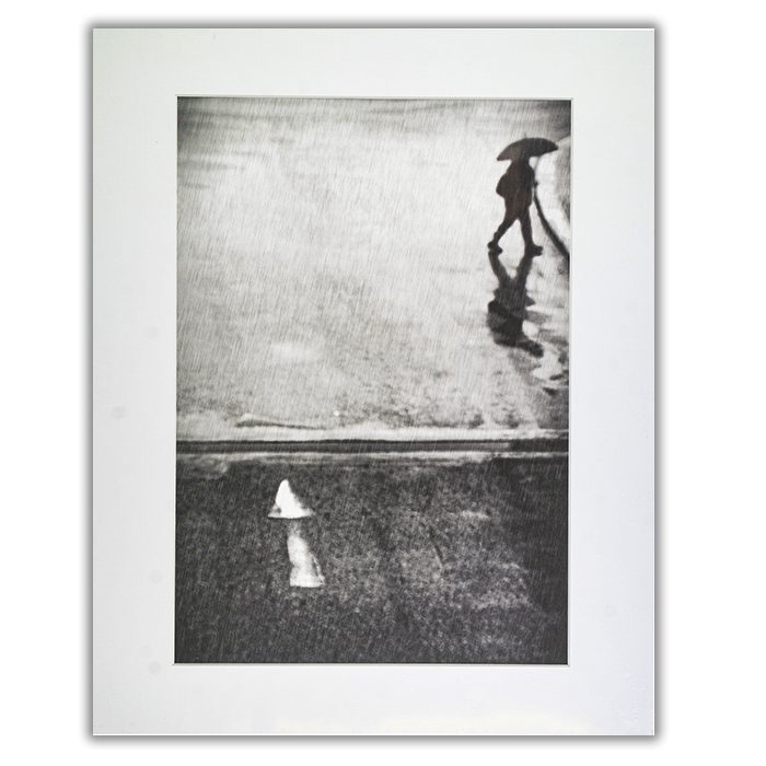 If I Have To Go Fotograf: Laura Mexia En svartvit suddig bild av regn och en person i siluett som går ut ur bilden med ett paraply