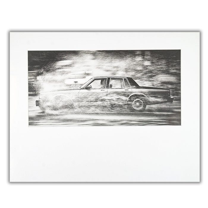 Dissection Fotograf: Hayk Shalunts En svartvit bild av en bil som åker genom vatten så det skvätter runt hela bilen