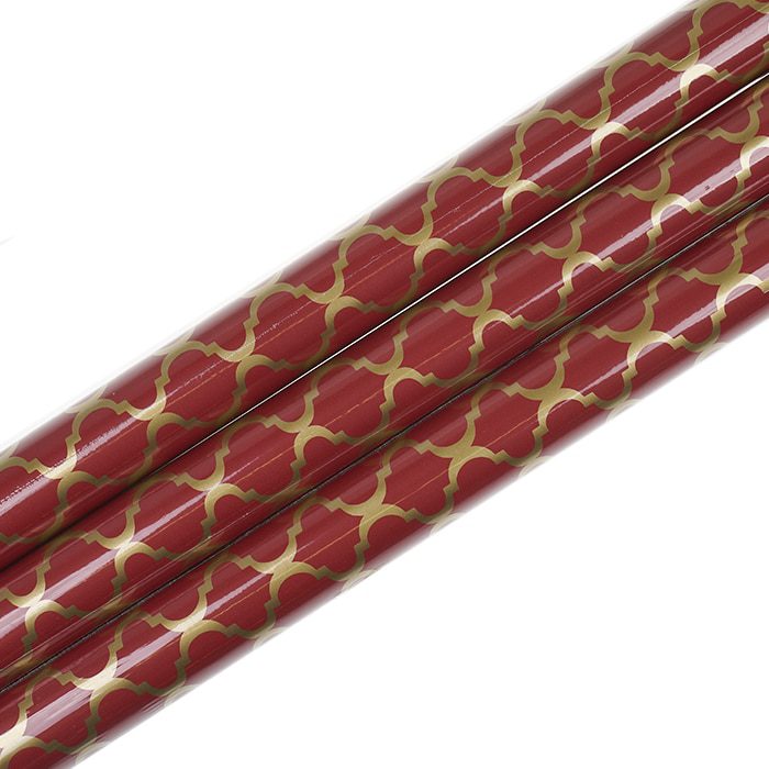 Tre rullar med rött presentpapper med guldmönster