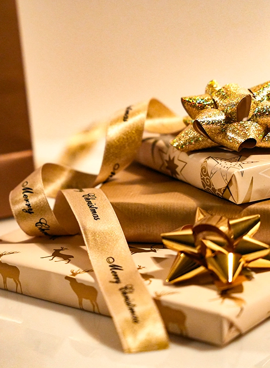 Flera vackra paket med olika presentpapper i guld och vitt. Band och rosetter i guld